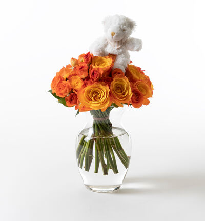 Oransje rosebukett med vase og bamse